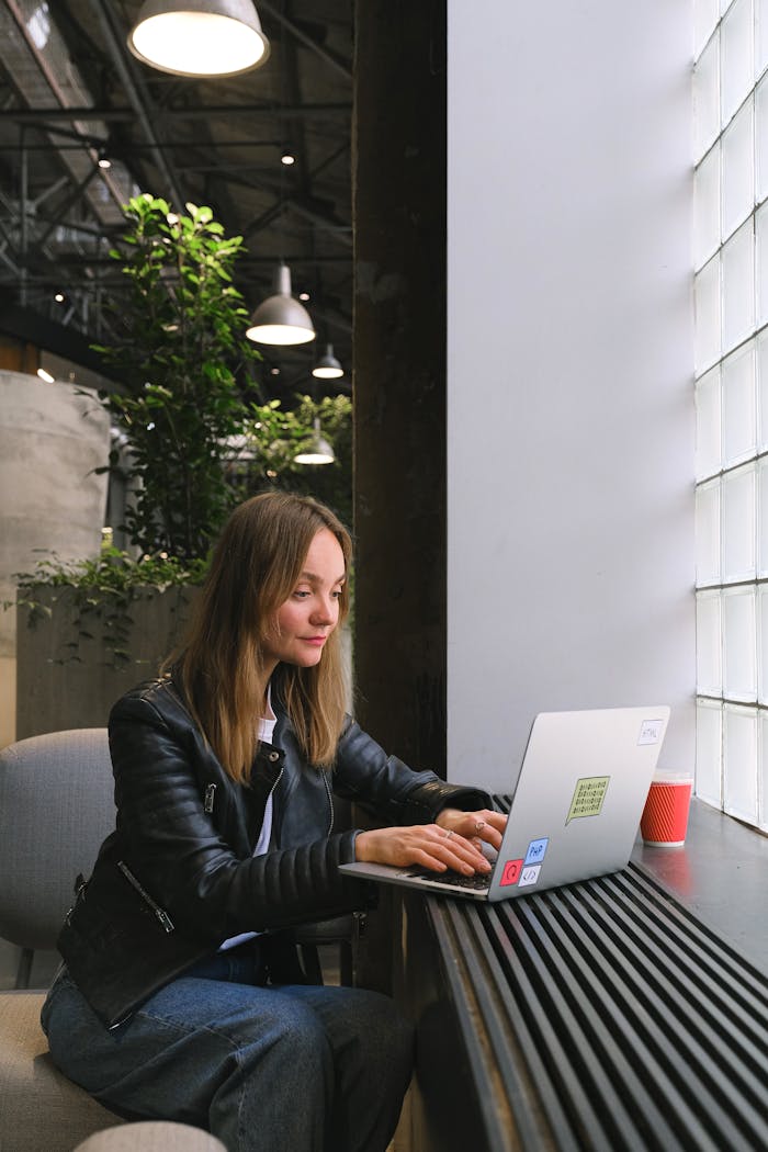 Woman freelancer using laptop indoors in a stylish office setting with natural light.